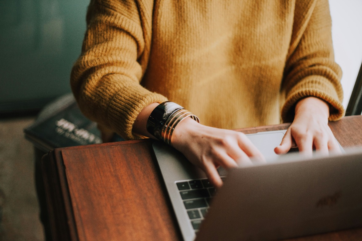 Lady in brown sweater typing on laptop